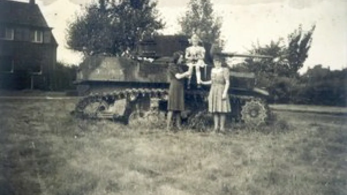 Zwei Frauen und ein Kind vor einem abgeschossenen Panzer