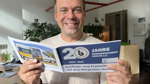 BM hinter der  Broschüre 20 Jahre Bürgerbus Anrath 